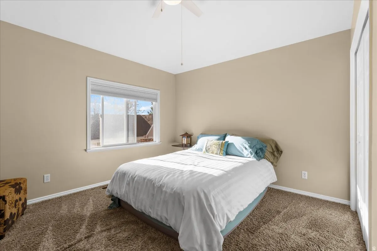 Carpeted bedroom featuring baseboards and ceiling fan
