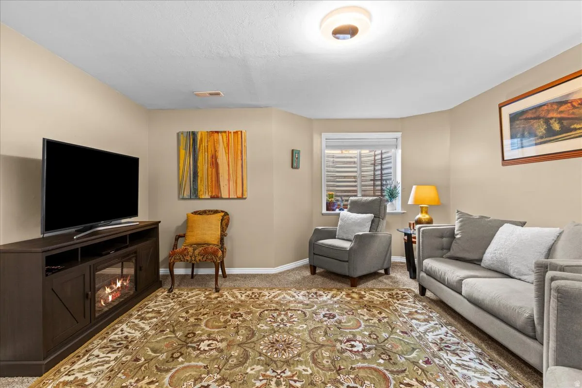 Living room with carpet floors and a glass covered fireplace