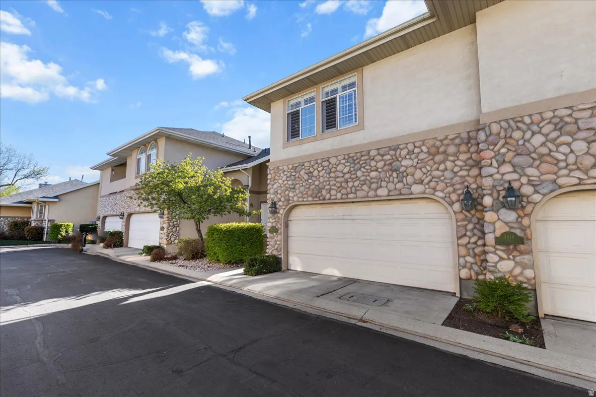 View of front of property with stucco siding, a garage, and stone siding