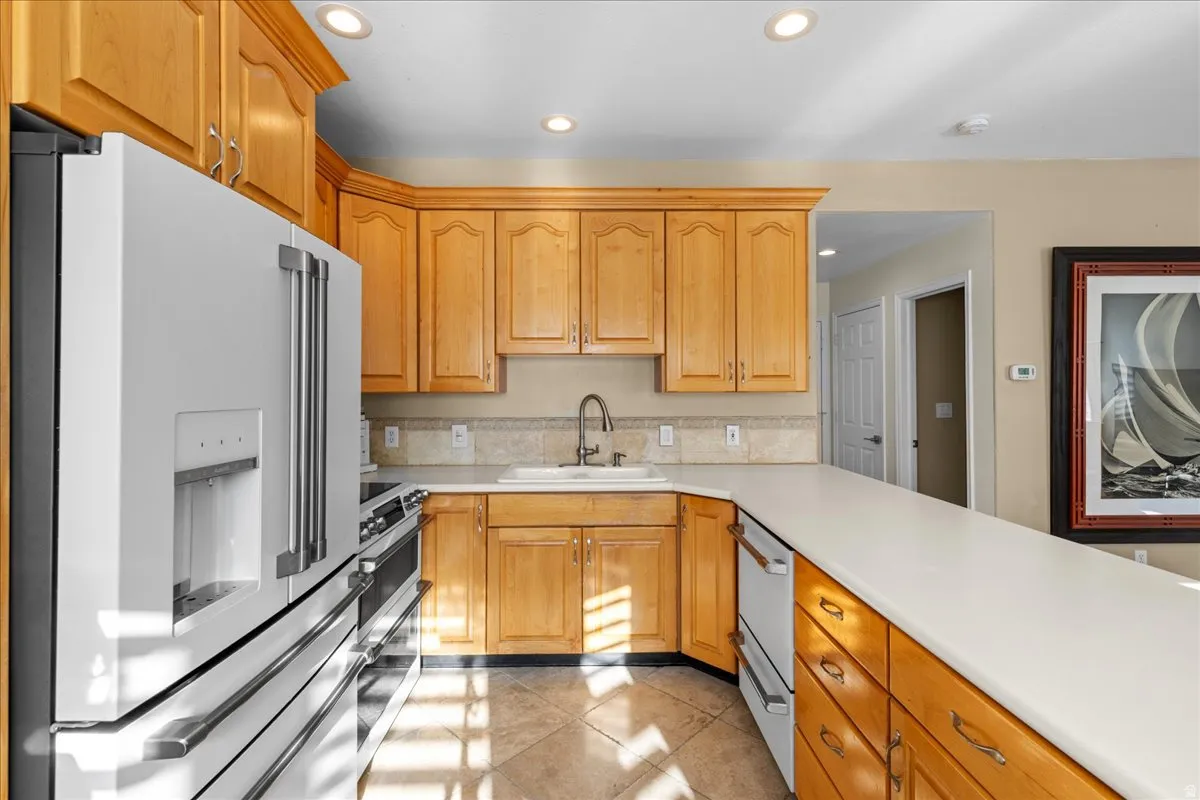 Kitchen with high end refrigerator, recessed lighting, light countertops, white dishwasher, and double oven range