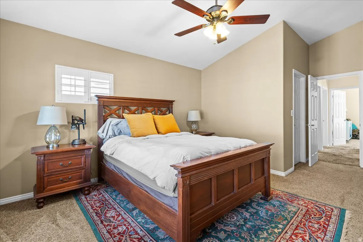 Bedroom featuring light carpet, vaulted ceiling, and ceiling fan