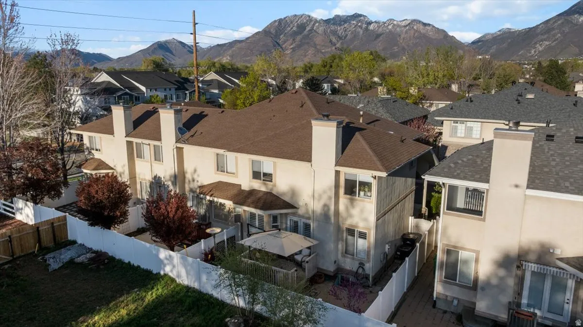 Rear view of property featuring a chimney, stucco siding, a residential view, a fenced backyard, and a mountain view