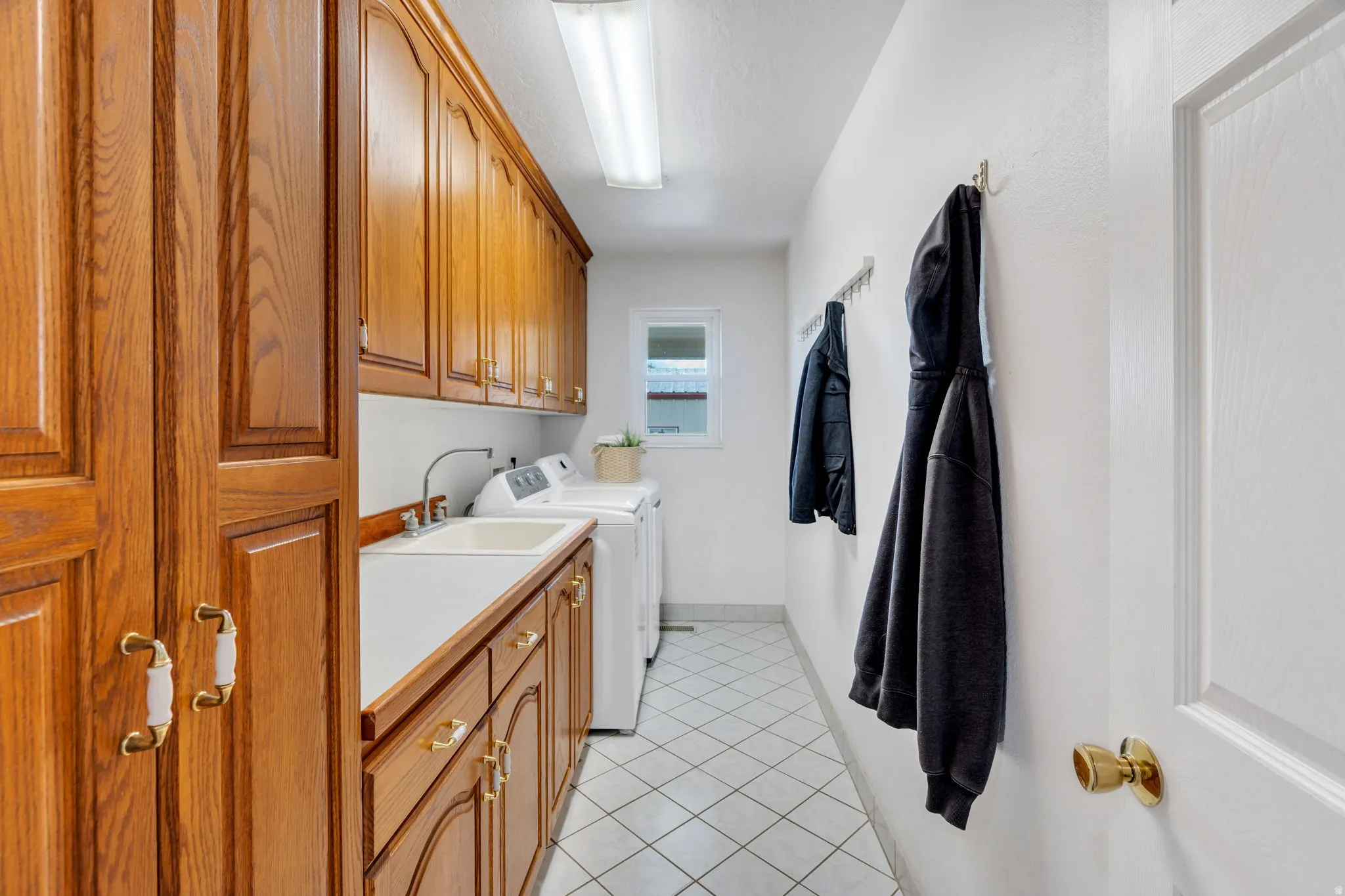 Laundry area featuring independent washer and dryer, light tile patterned floors, and cabinet space