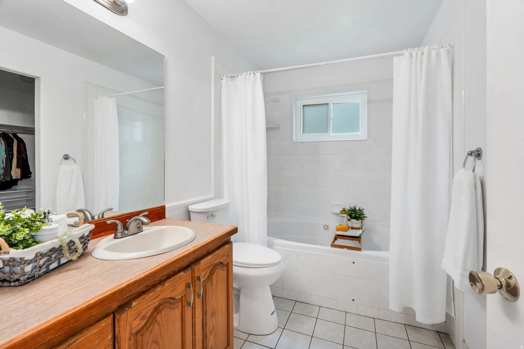 Bathroom featuring vanity, a walk in closet, light tile patterned floors, and tiled shower / bath combo