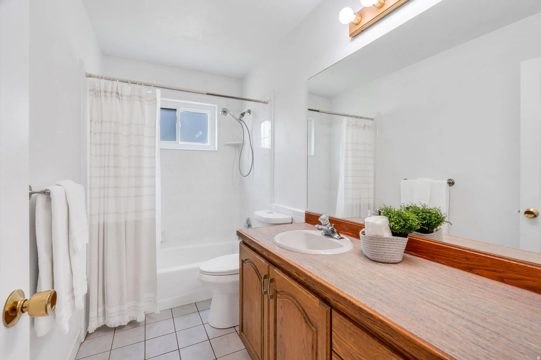 Full bath featuring vanity, light tile patterned floors, and shower / tub combo with curtain