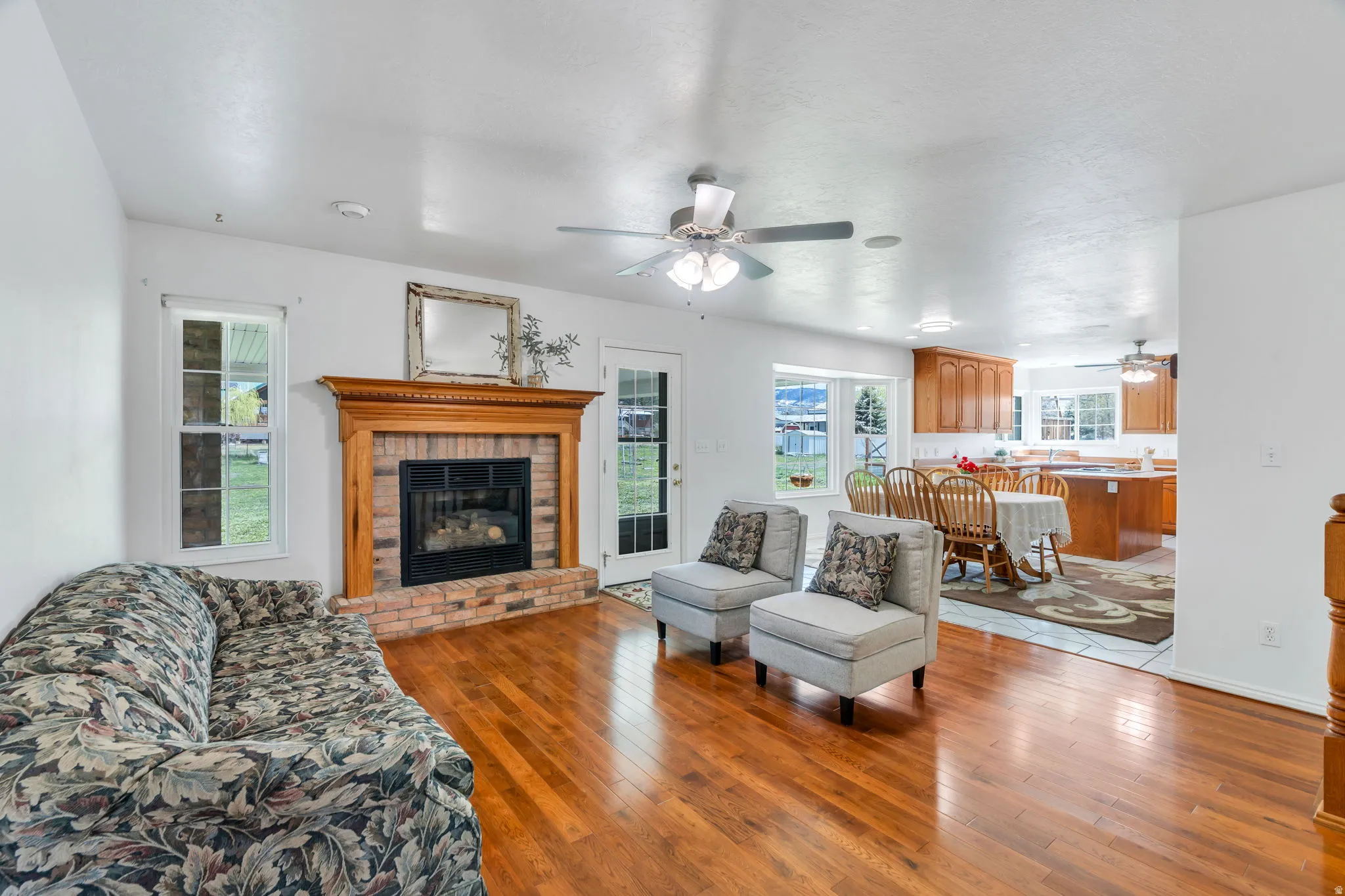 Living area featuring a fireplace, light wood-style flooring, and a ceiling fan