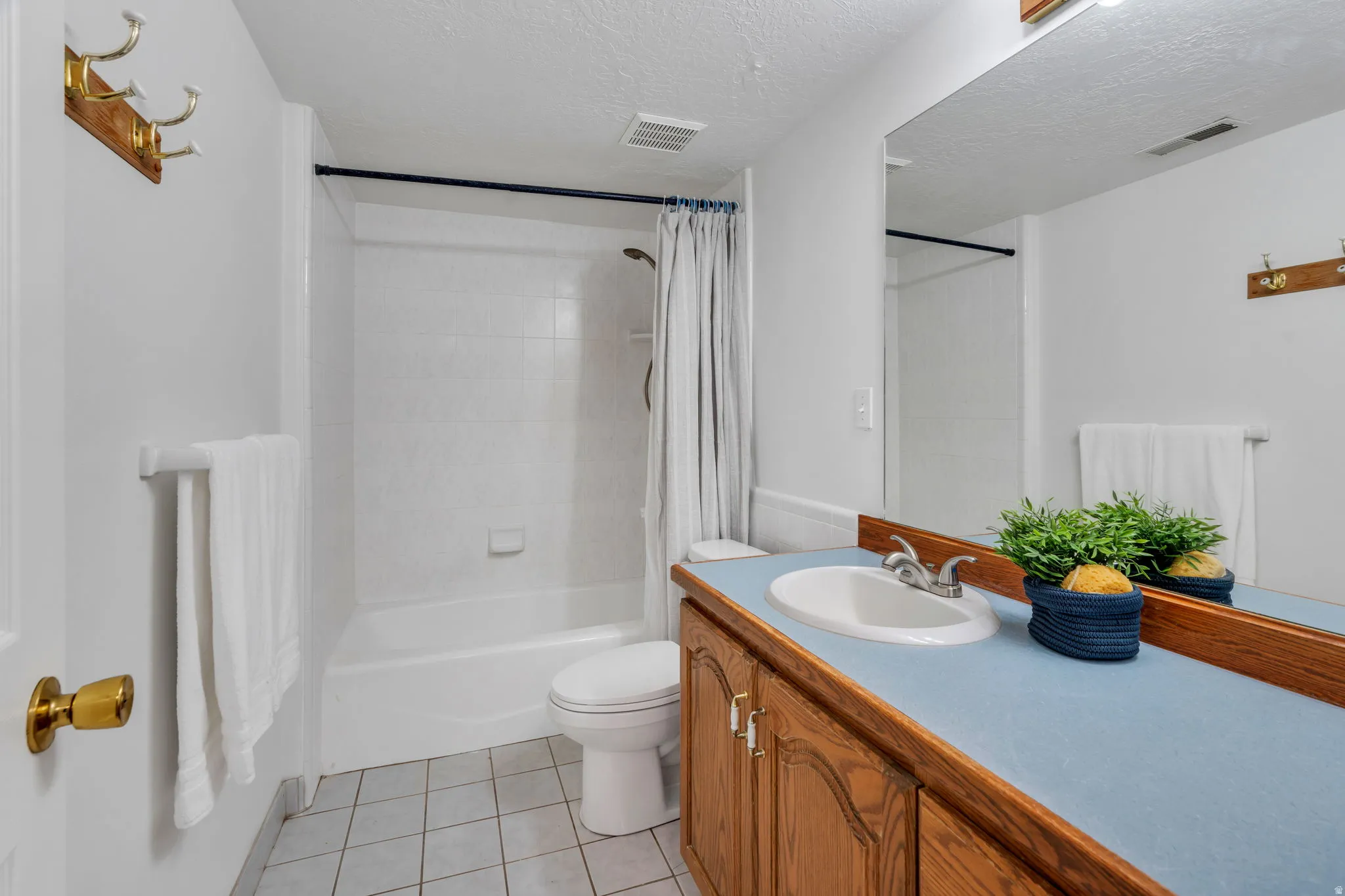 Full bathroom with vanity, light tile patterned flooring, shower / tub combo, and a textured ceiling