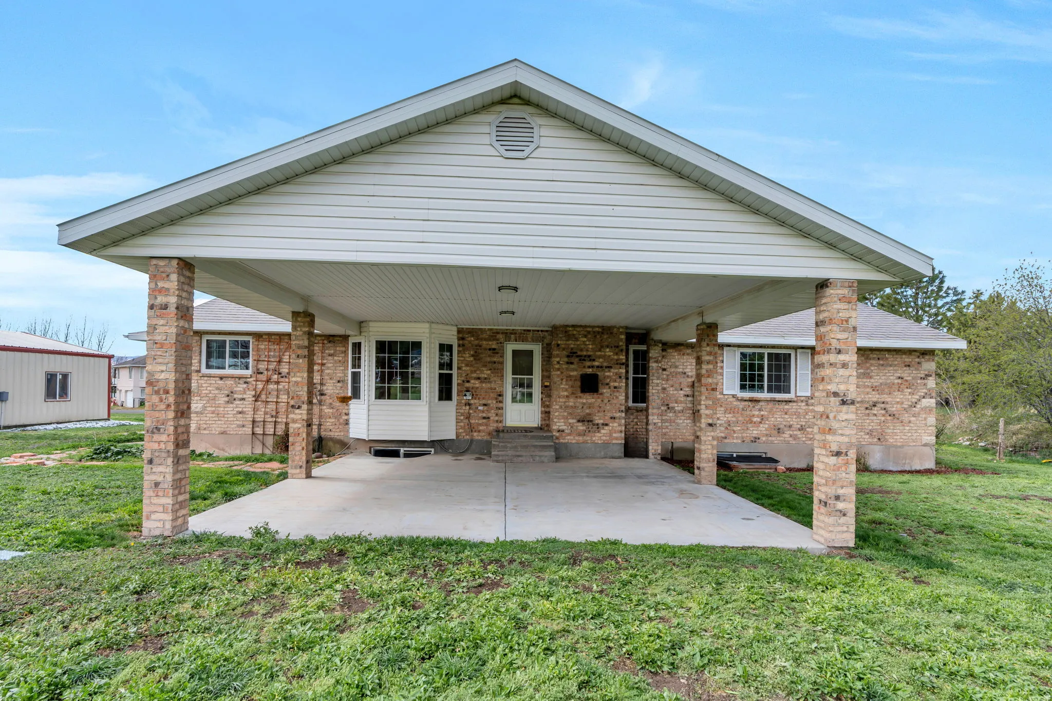 Back of house with brick siding, a yard, a patio area, and entry steps