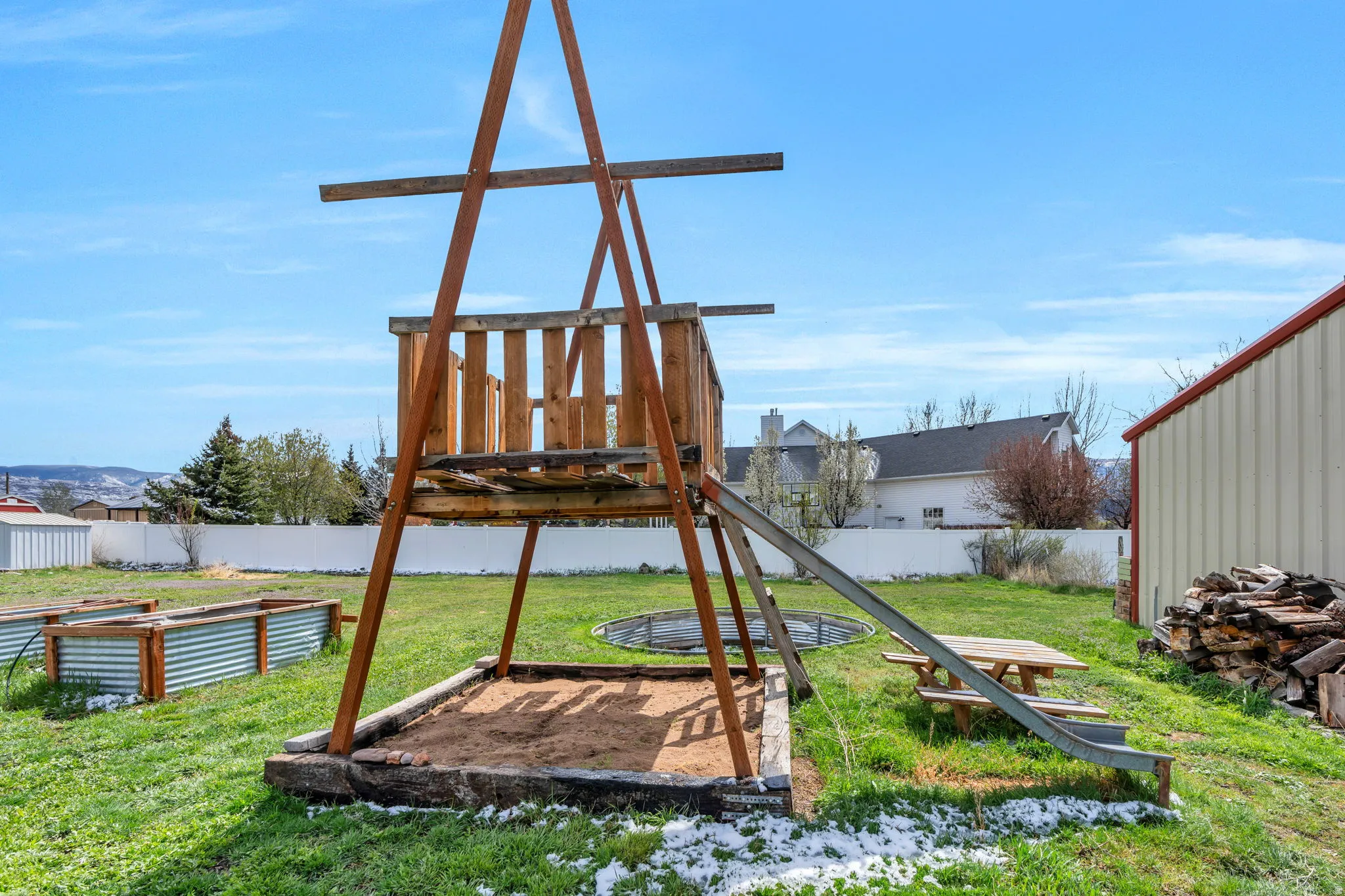 View of playground featuring a vegetable garden, a fenced backyard, and a patio area