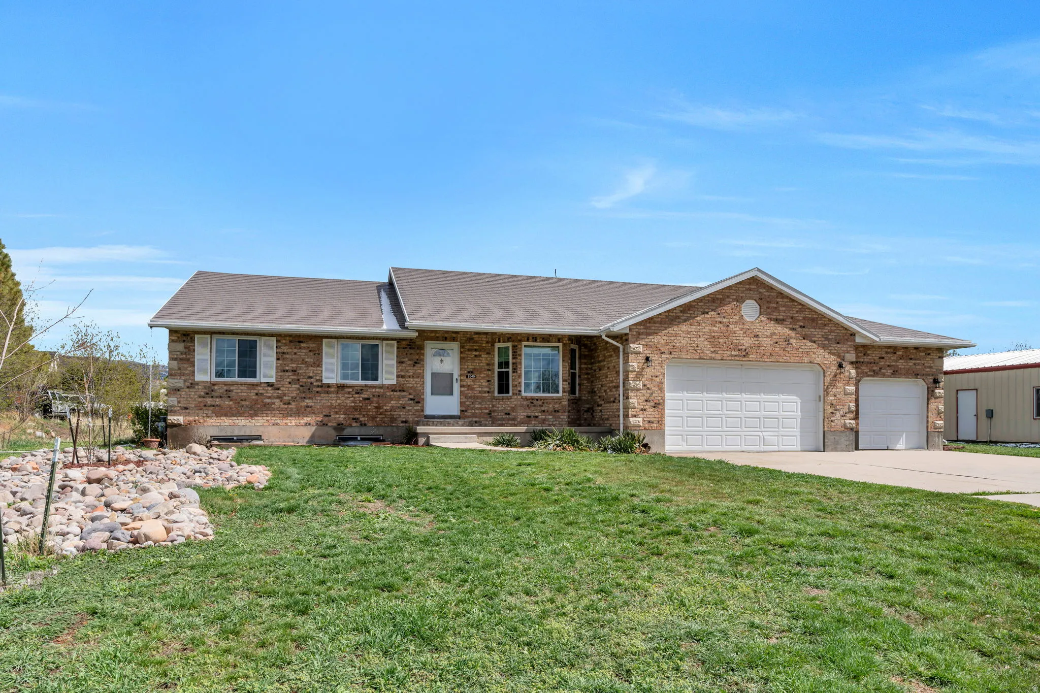 Ranch-style home featuring roof with shingles, a garage, a front lawn, and brick siding