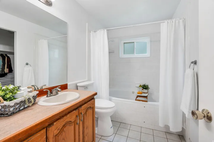 Bathroom featuring vanity, a walk in closet, light tile patterned floors, and tiled shower / bath combo