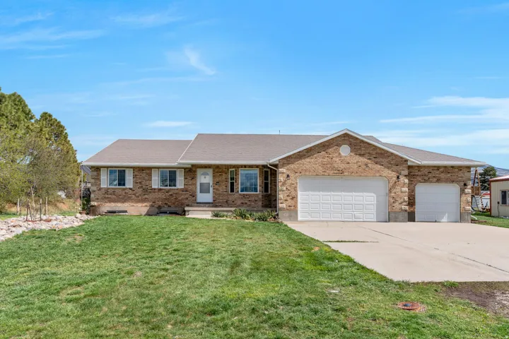 Single story home featuring an attached garage, roof with shingles, concrete driveway, and a front yard
