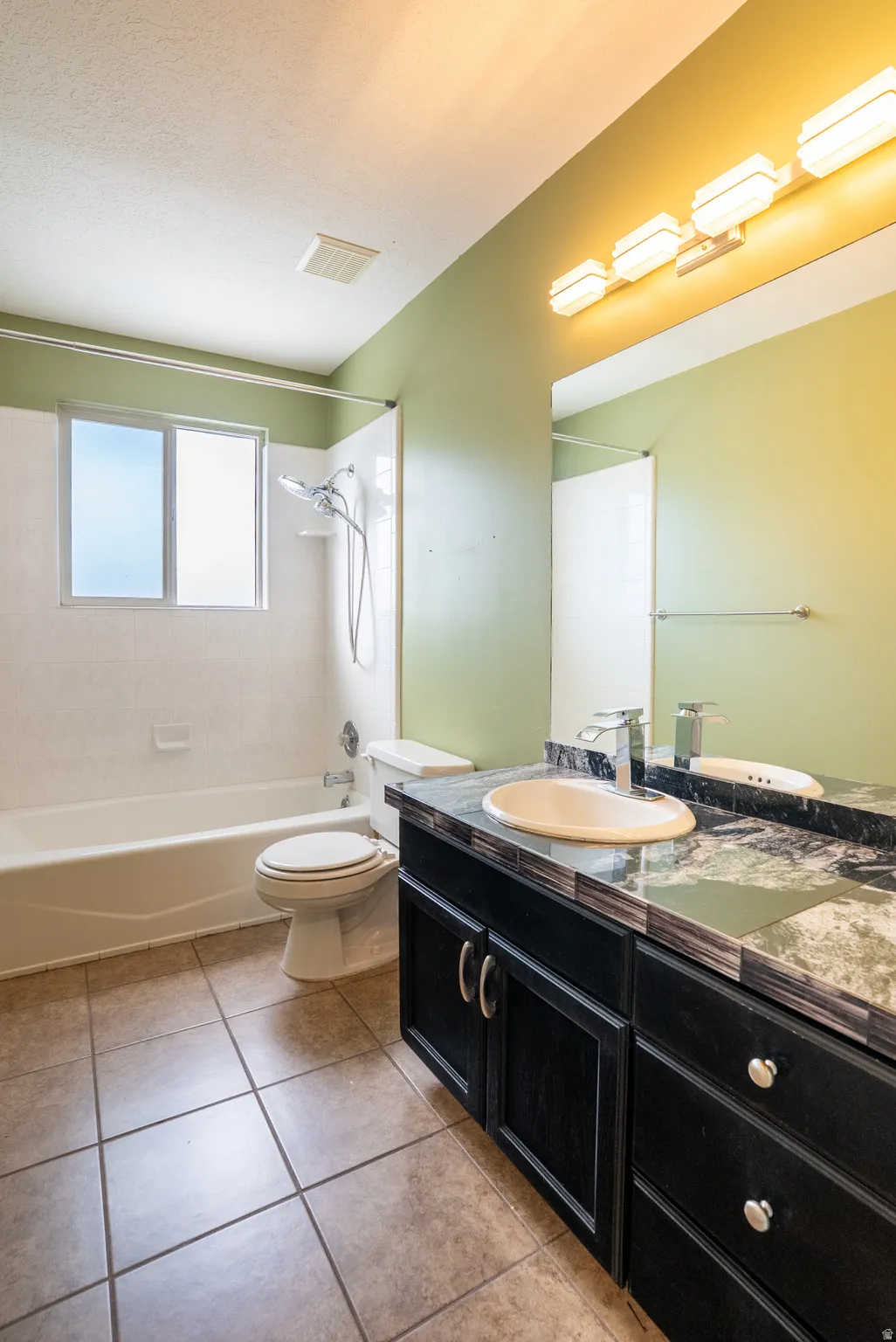 Bathroom featuring shower / tub combination, vanity, and light tile patterned flooring