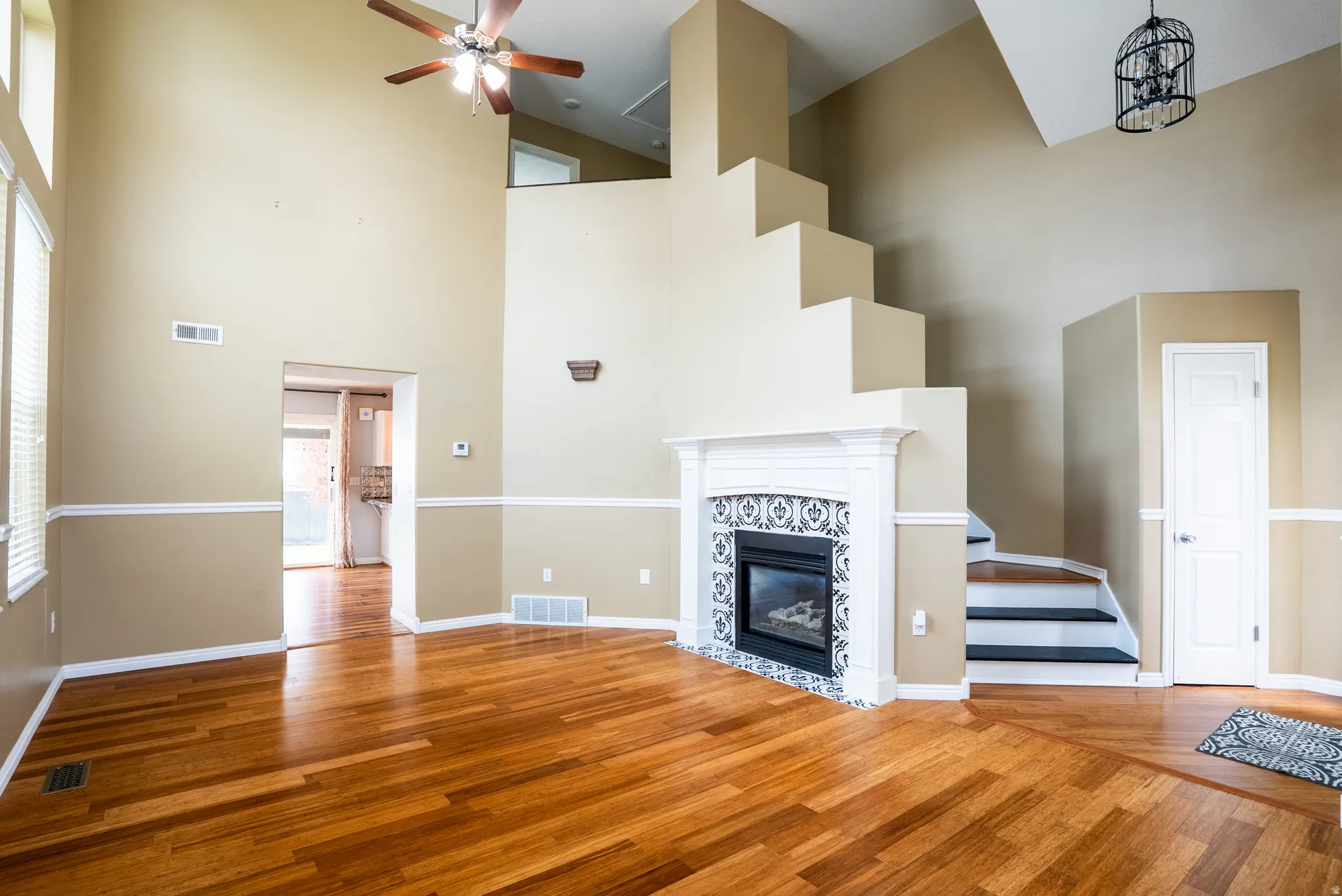 Unfurnished living room with a tile fireplace, wood finished floors, a high ceiling, and a ceiling fan