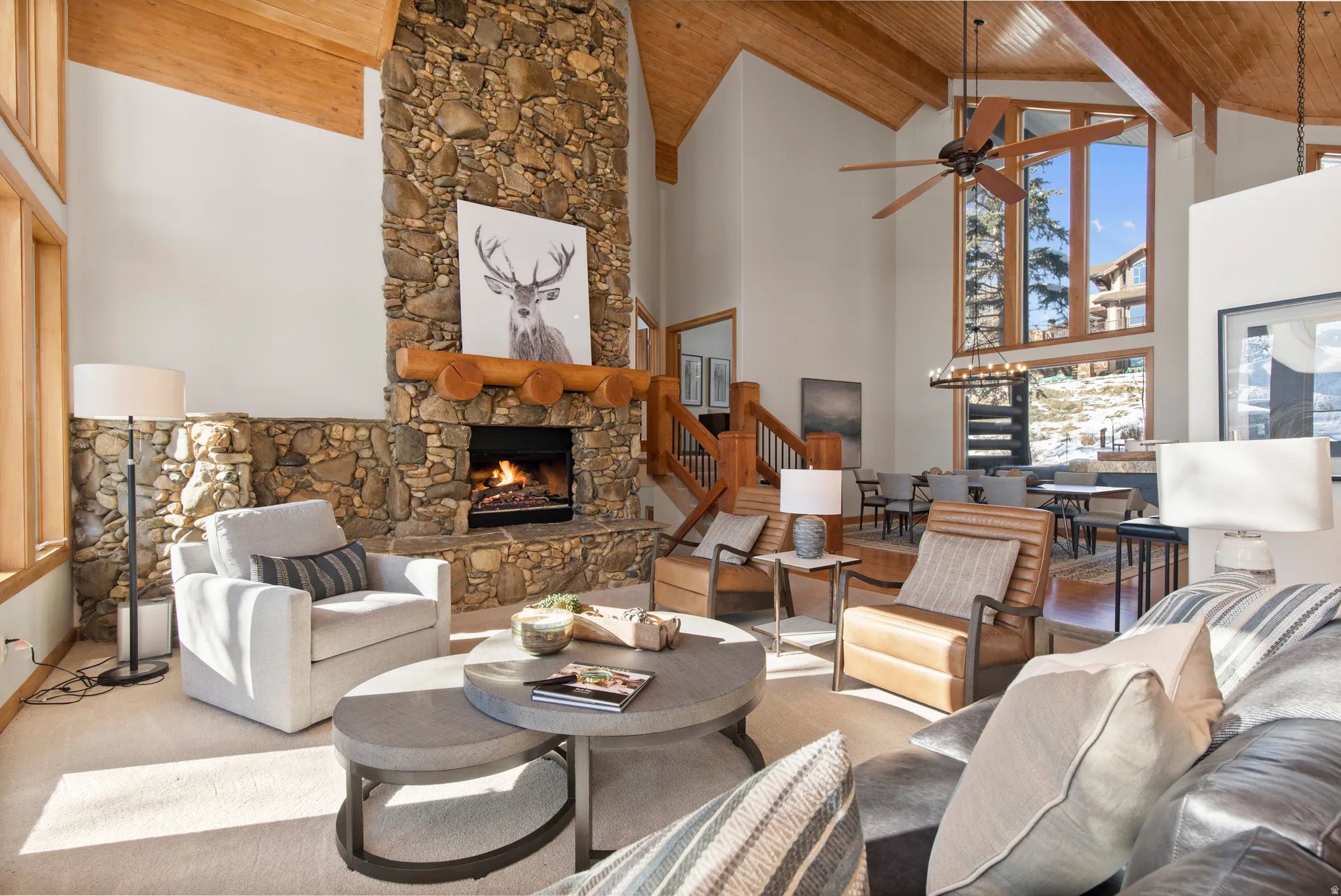 Living area with a stone fireplace, a high wooden beamed ceiling, and a ceiling fan