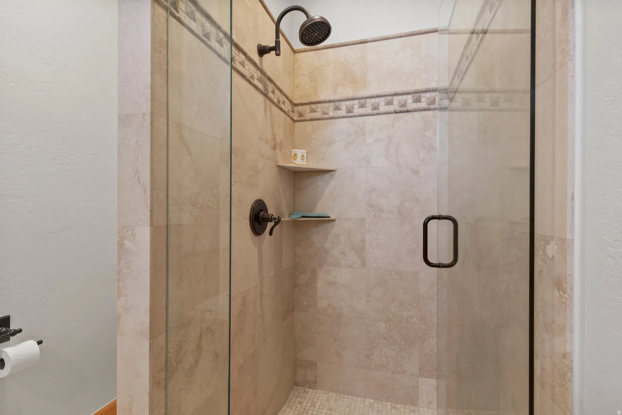 Full bathroom with a shower stall and a textured wall