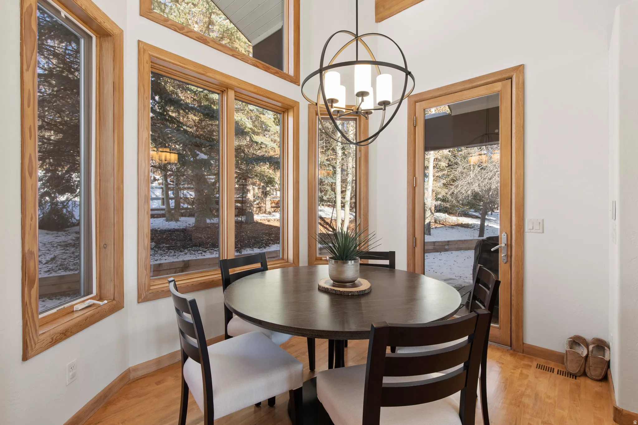 Dining room with light wood-style flooring, suspended lighting, and vaulted ceiling