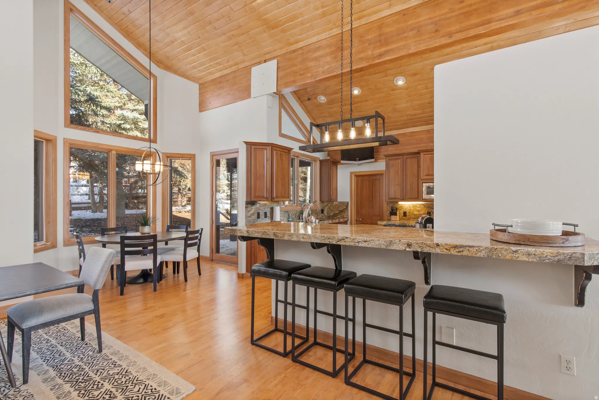 Kitchen with wood finish cabinets, a vaulted wood ceiling, a chandelier, a kitchen breakfast bar, and light wood finished floors