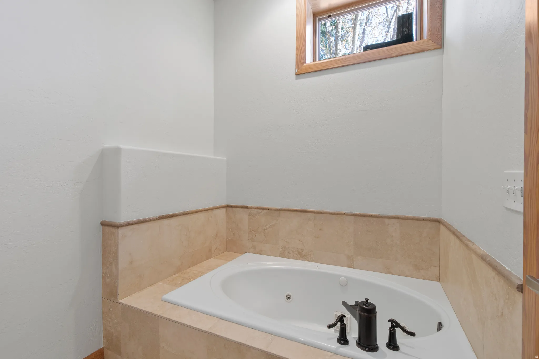 Bathroom featuring a whirlpool tub and a textured wall