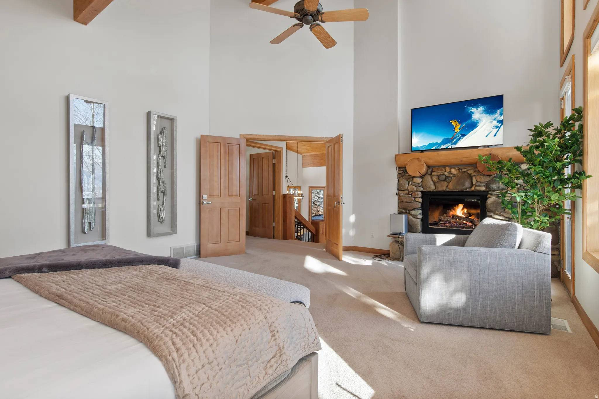 Bedroom with carpet flooring, a high ceiling, a stone fireplace, and ceiling fan