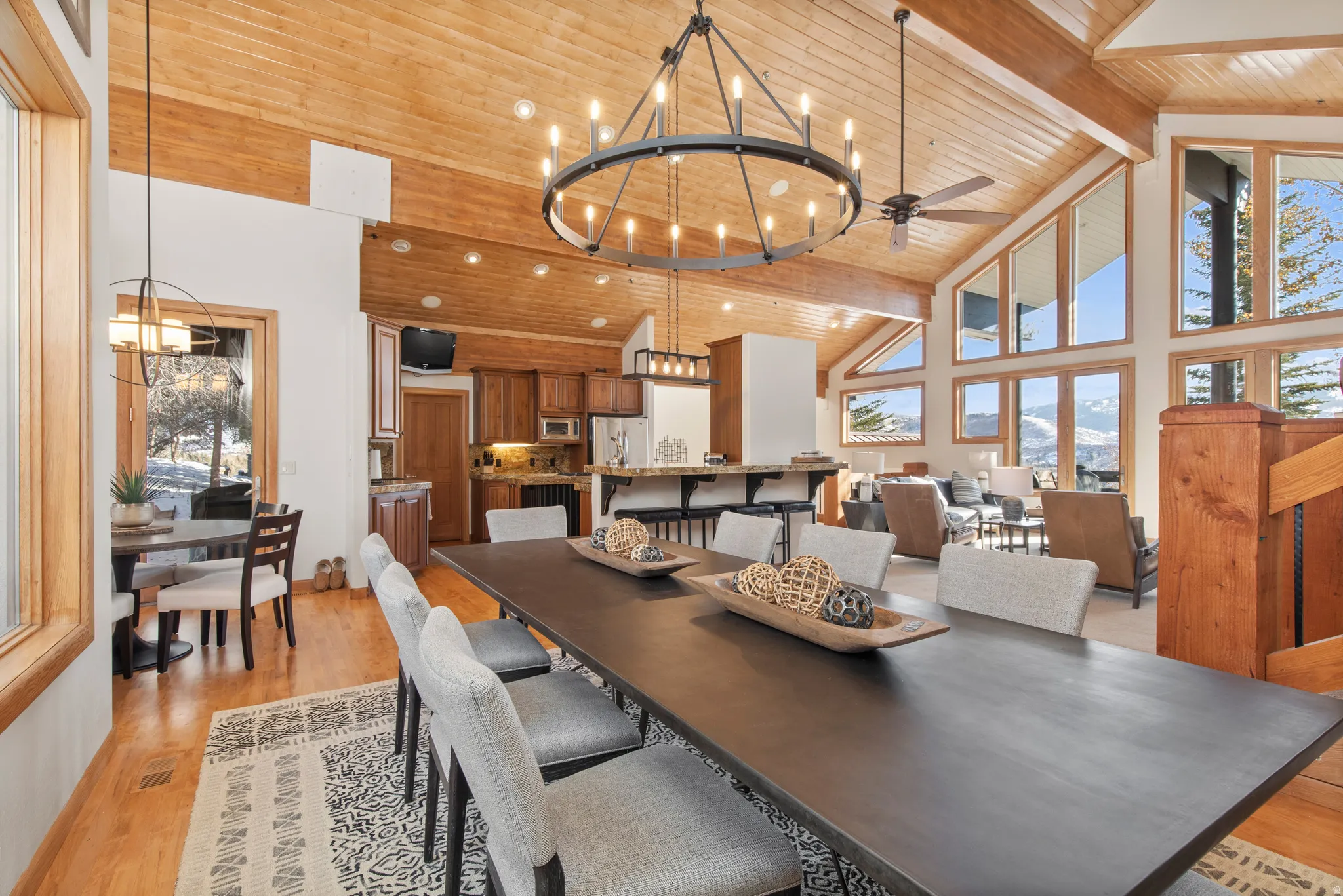 Dining space featuring a chandelier, a high wood beamed ceiling, light wood-type flooring, and a ceiling fan