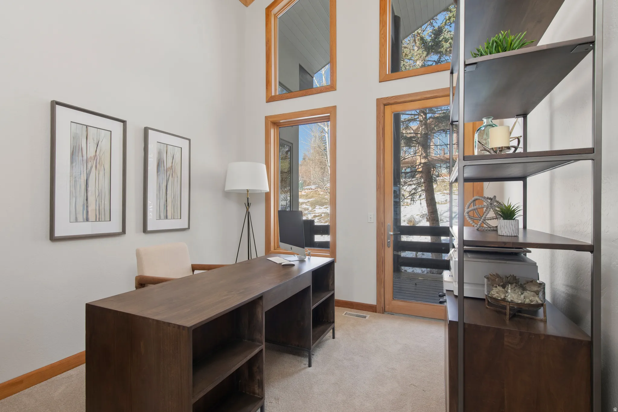 Home office with light colored carpet and a high ceiling