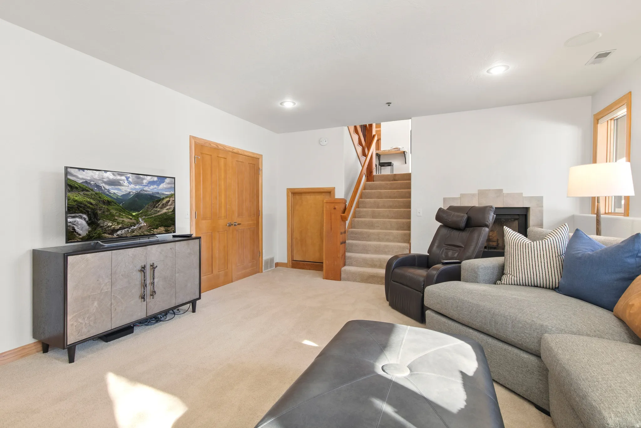 Living room with light carpet, recessed lighting, and a tile fireplace