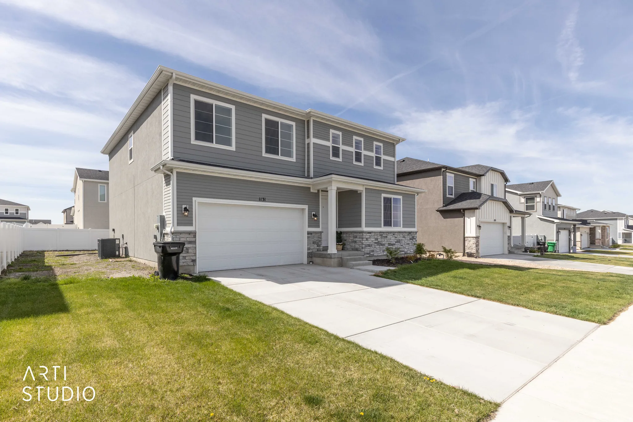 View of front of property featuring stone siding, an attached garage, driveway, a residential view, and a front yard