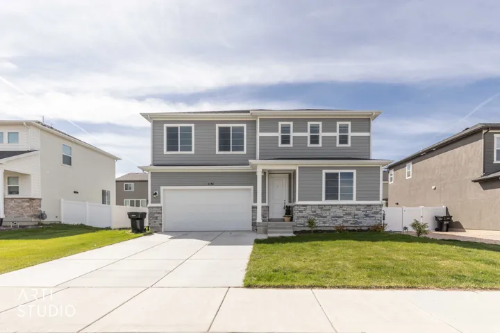 View of front of house featuring stone siding, a garage, and concrete driveway