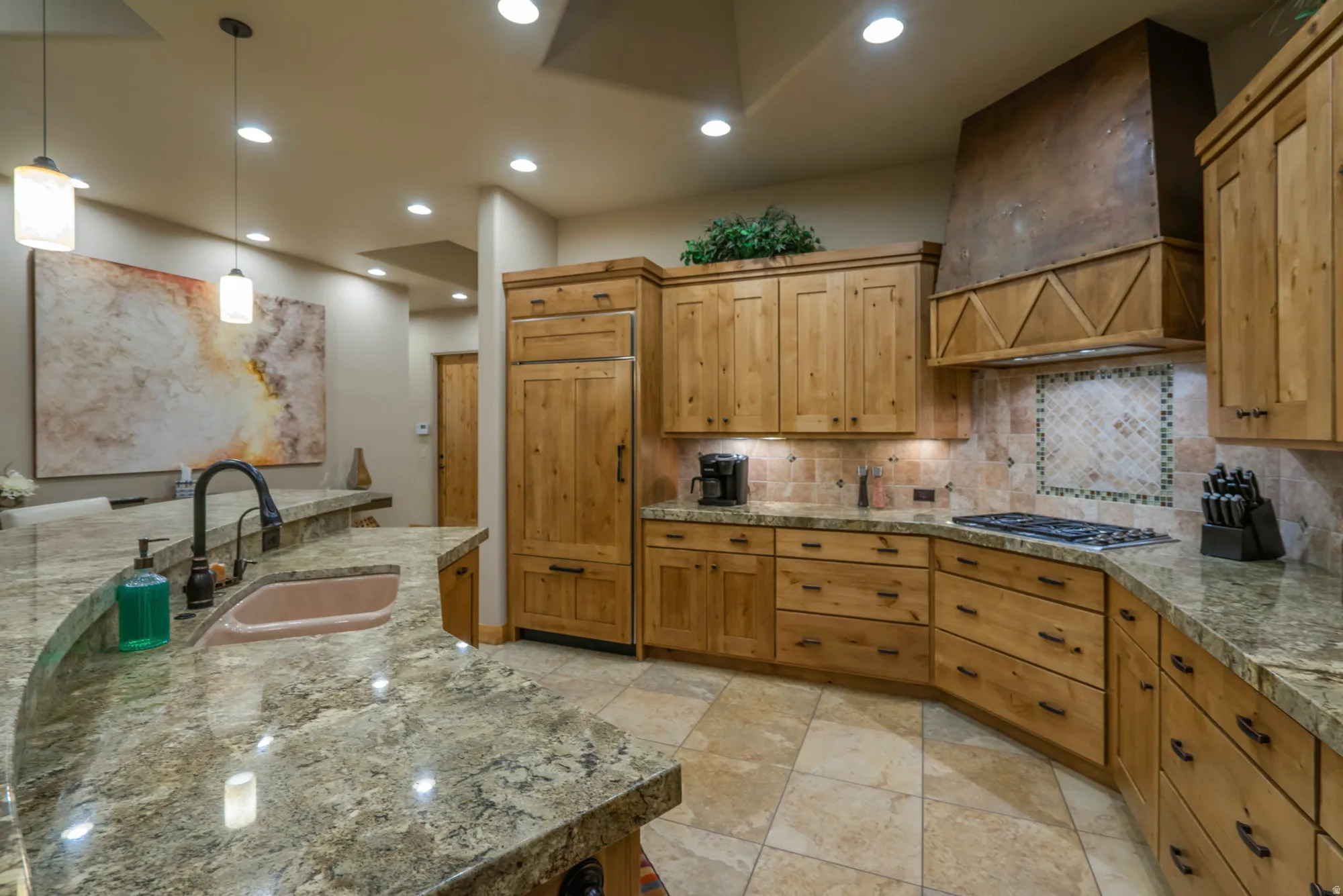 Kitchen with pendant lighting, tasteful backsplash, wood finish cabinets, paneled fridge, and stainless steel gas cooktop
