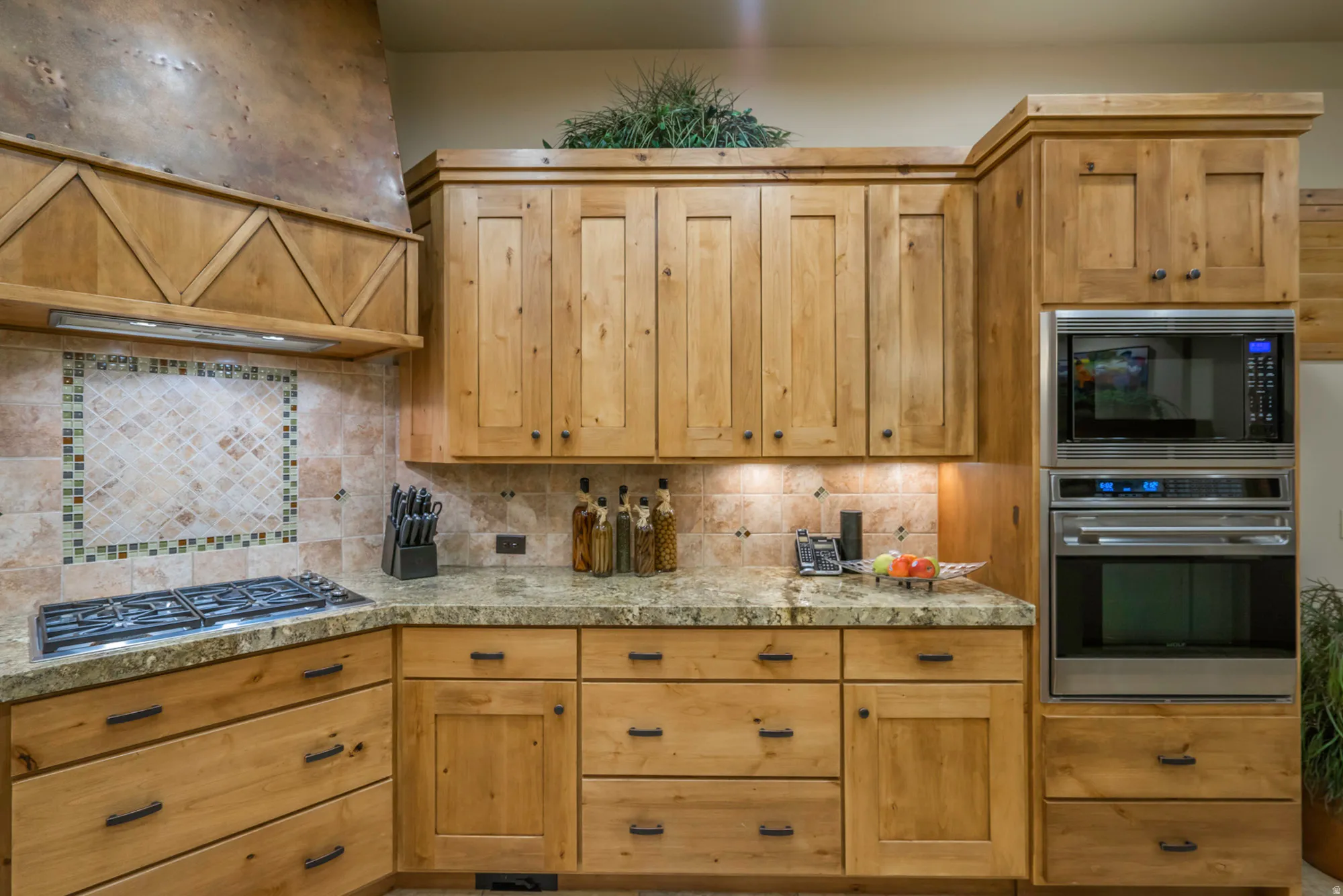 Kitchen featuring stainless steel appliances, range hood, tile countertops, and backsplash