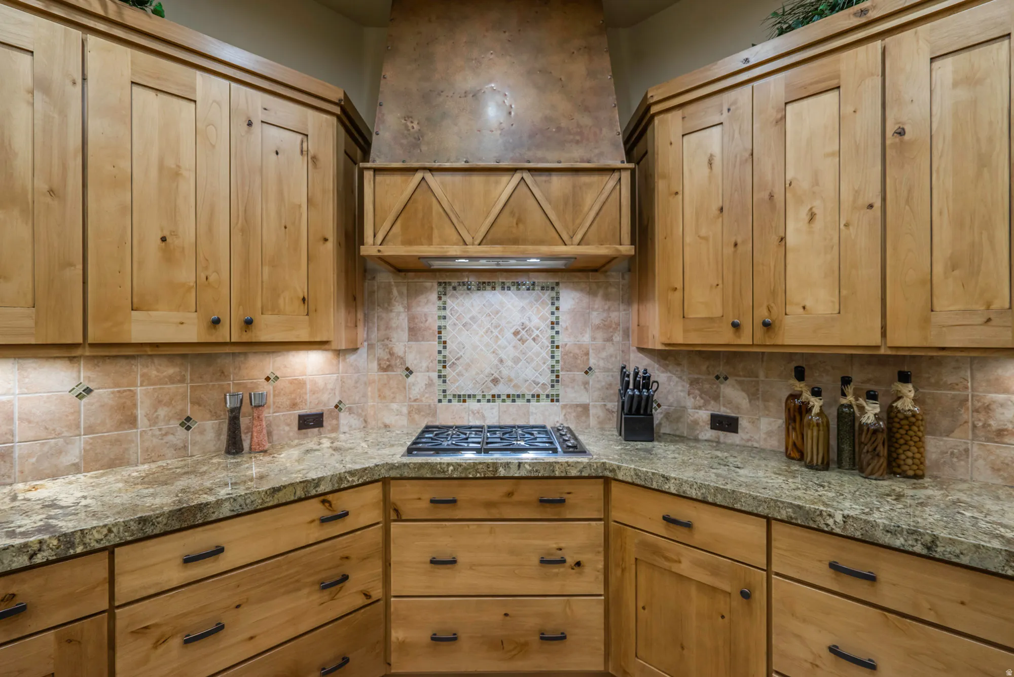 Kitchen with stainless steel gas stovetop, light wood finish cabinets, and tasteful backsplash