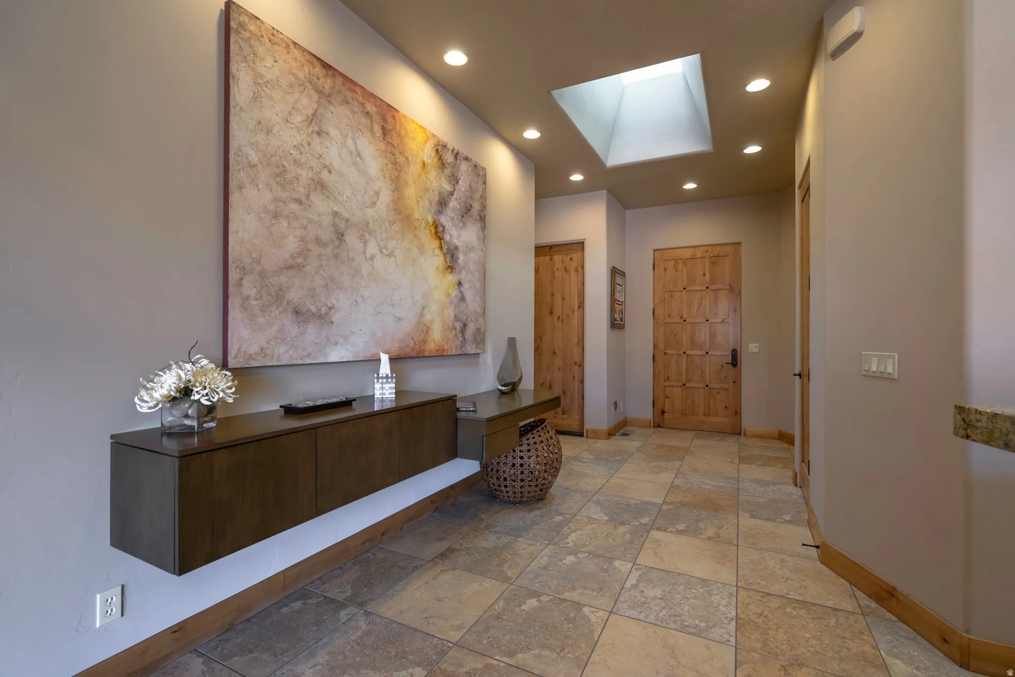 Hallway with a skylight, light stone finish floors, and recessed lighting