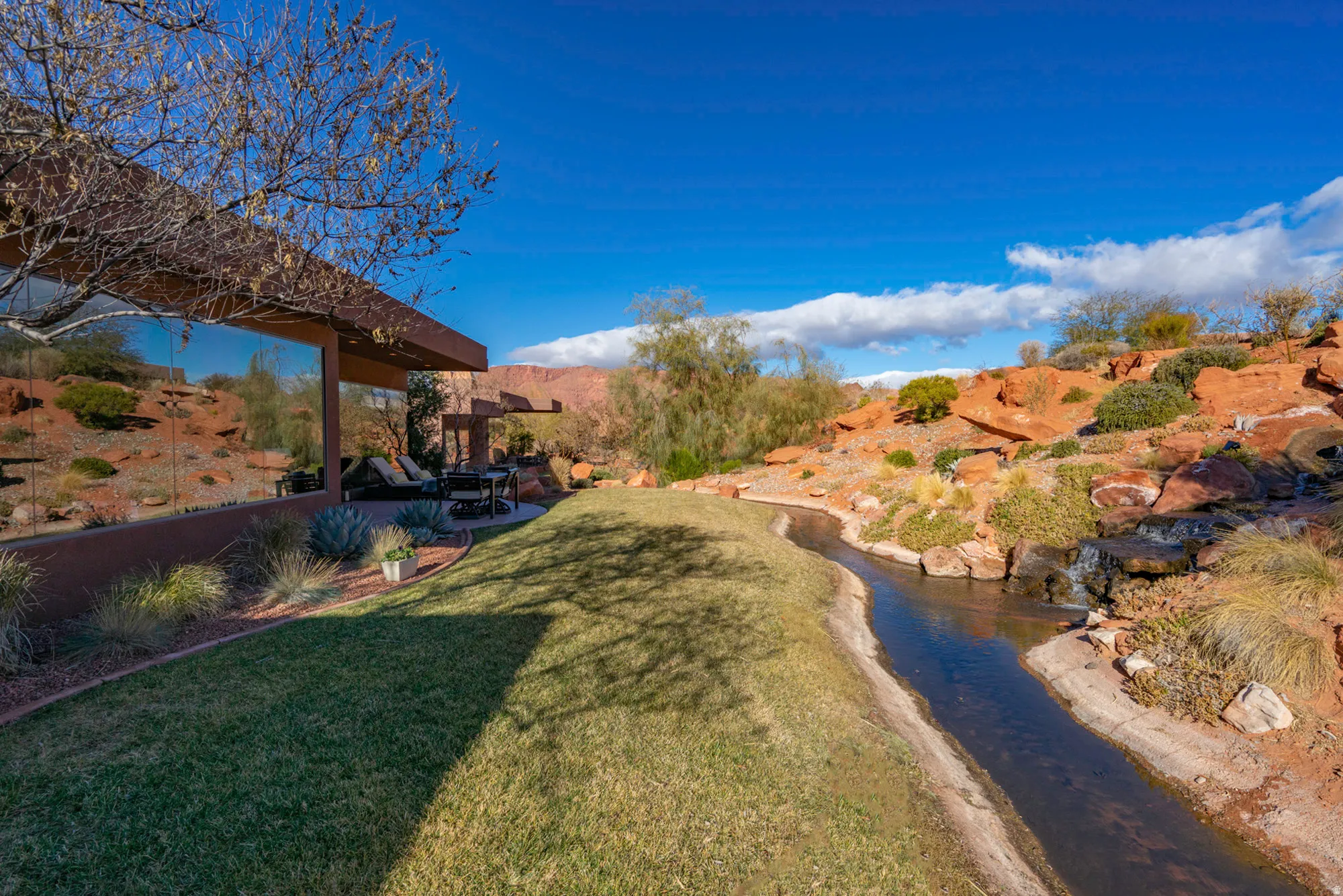 View of grassy yard featuring a garden pond and a patio