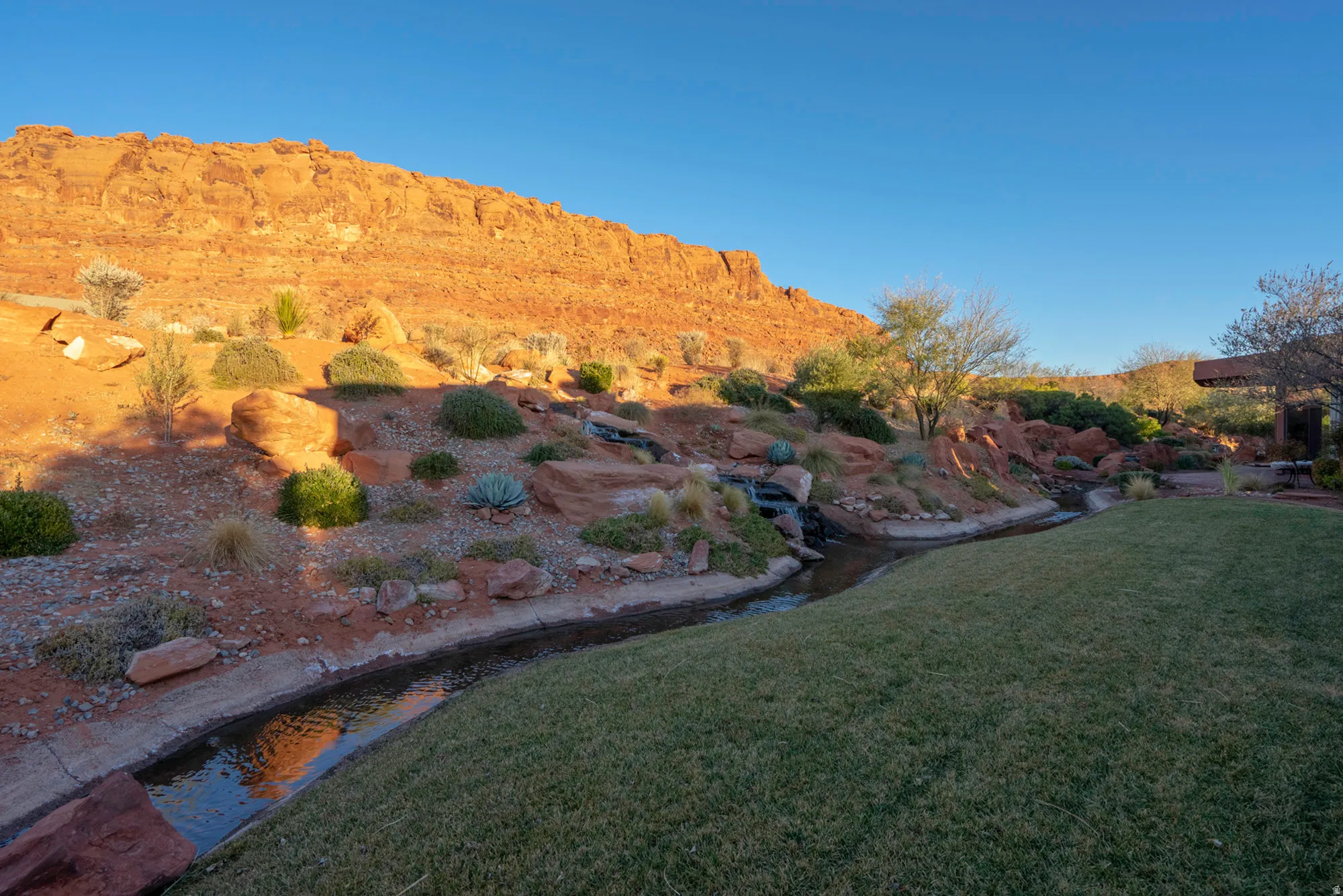 View of grassy yard with a mountain view and a garden pond