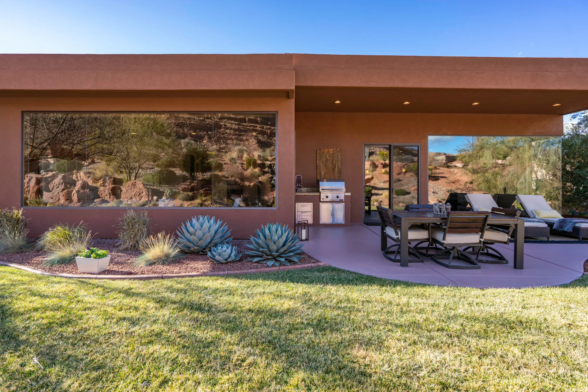 Rear view of property featuring a patio area, stucco siding, and a lawn