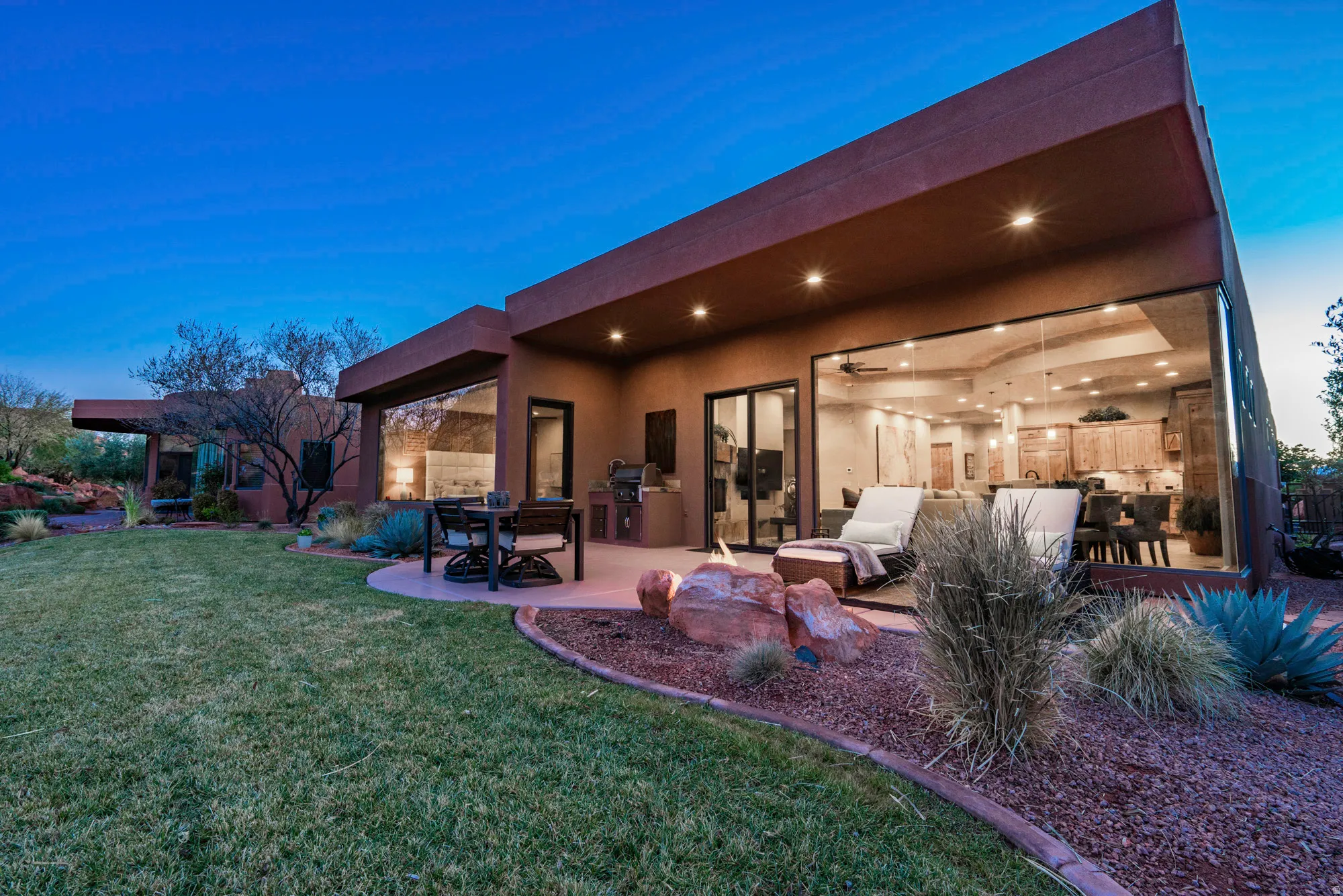 Back of property at dusk with stucco siding, a patio, a yard, and outdoor dining space