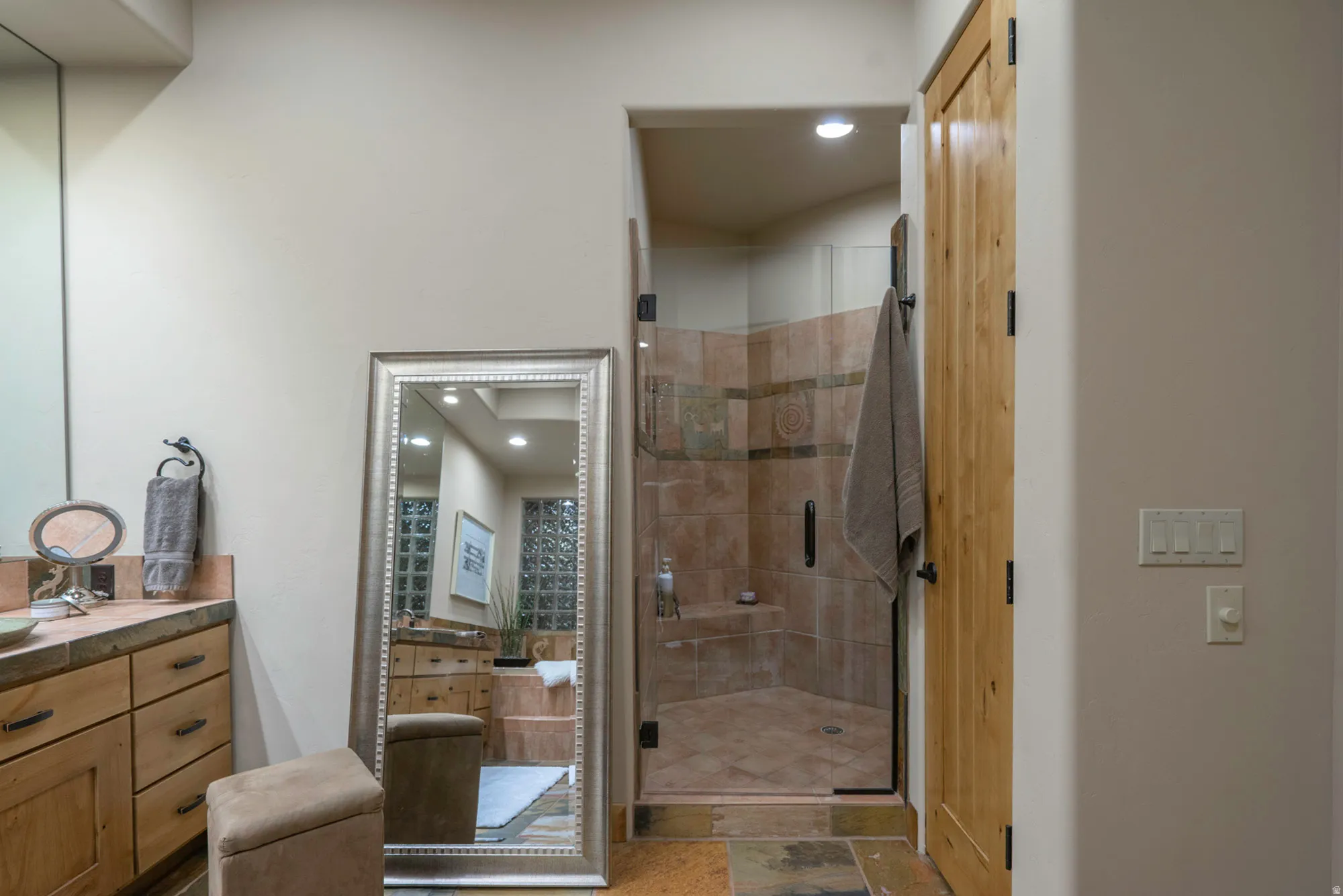 Full bath featuring vanity, a shower stall, and stone tile flooring