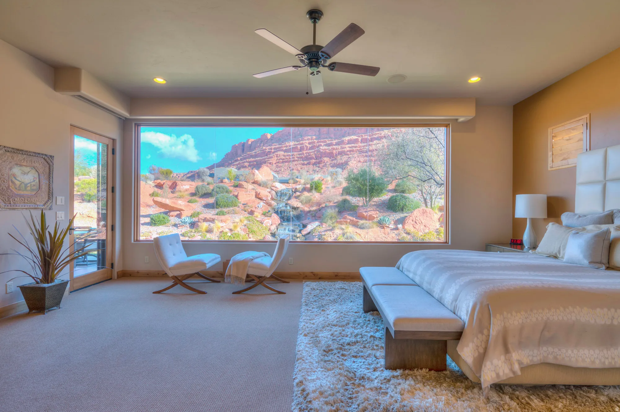 Carpeted bedroom featuring access to outside, a ceiling fan, multiple windows, and a mountain view