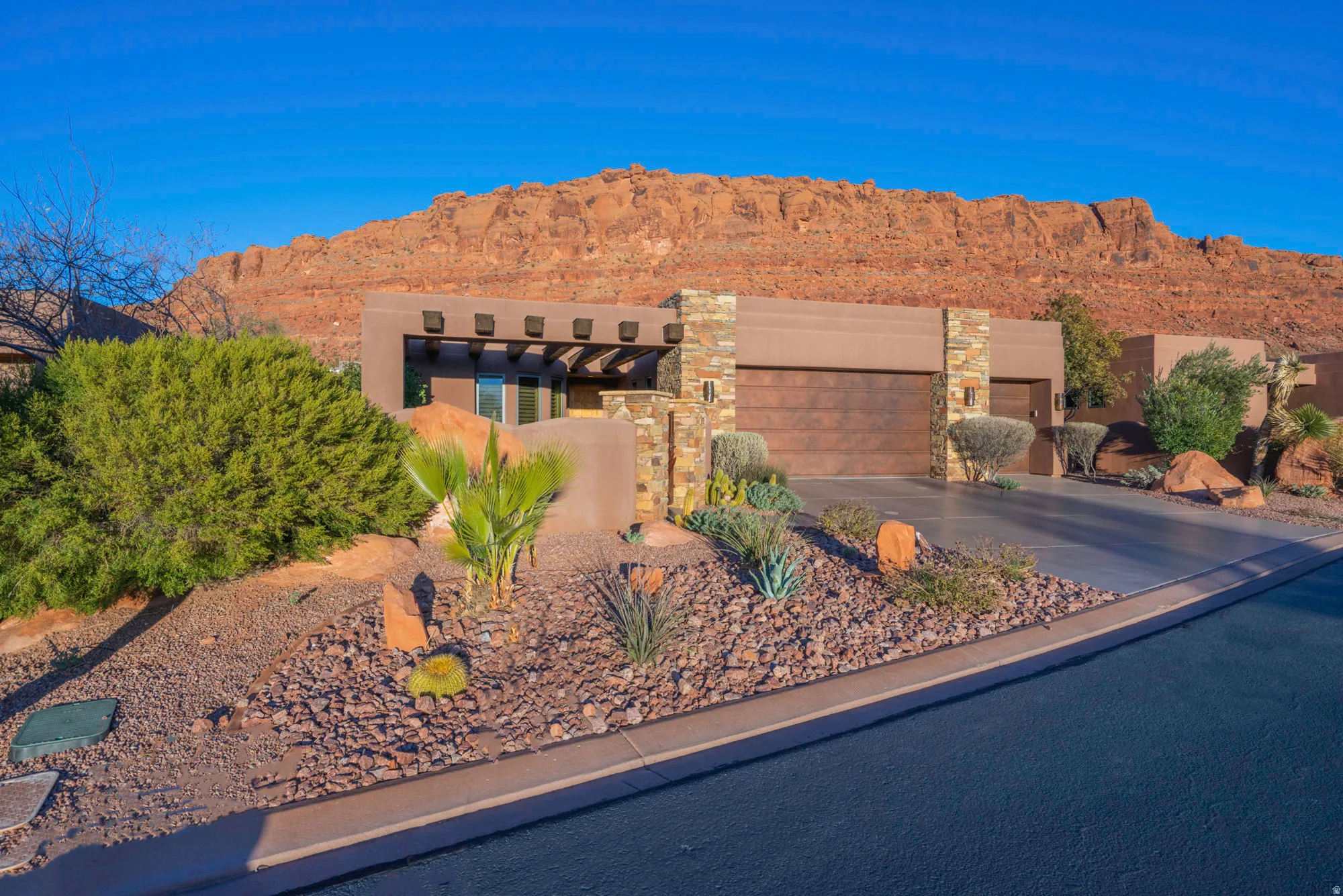 View of front of property featuring an attached garage, a mountain view, stone siding, driveway, and stucco siding