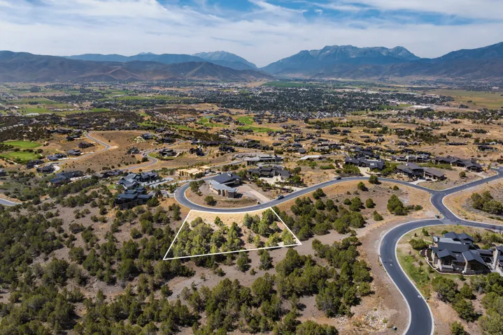 Aerial perspective of suburban area featuring a mountain backdrop and property parcel outlined