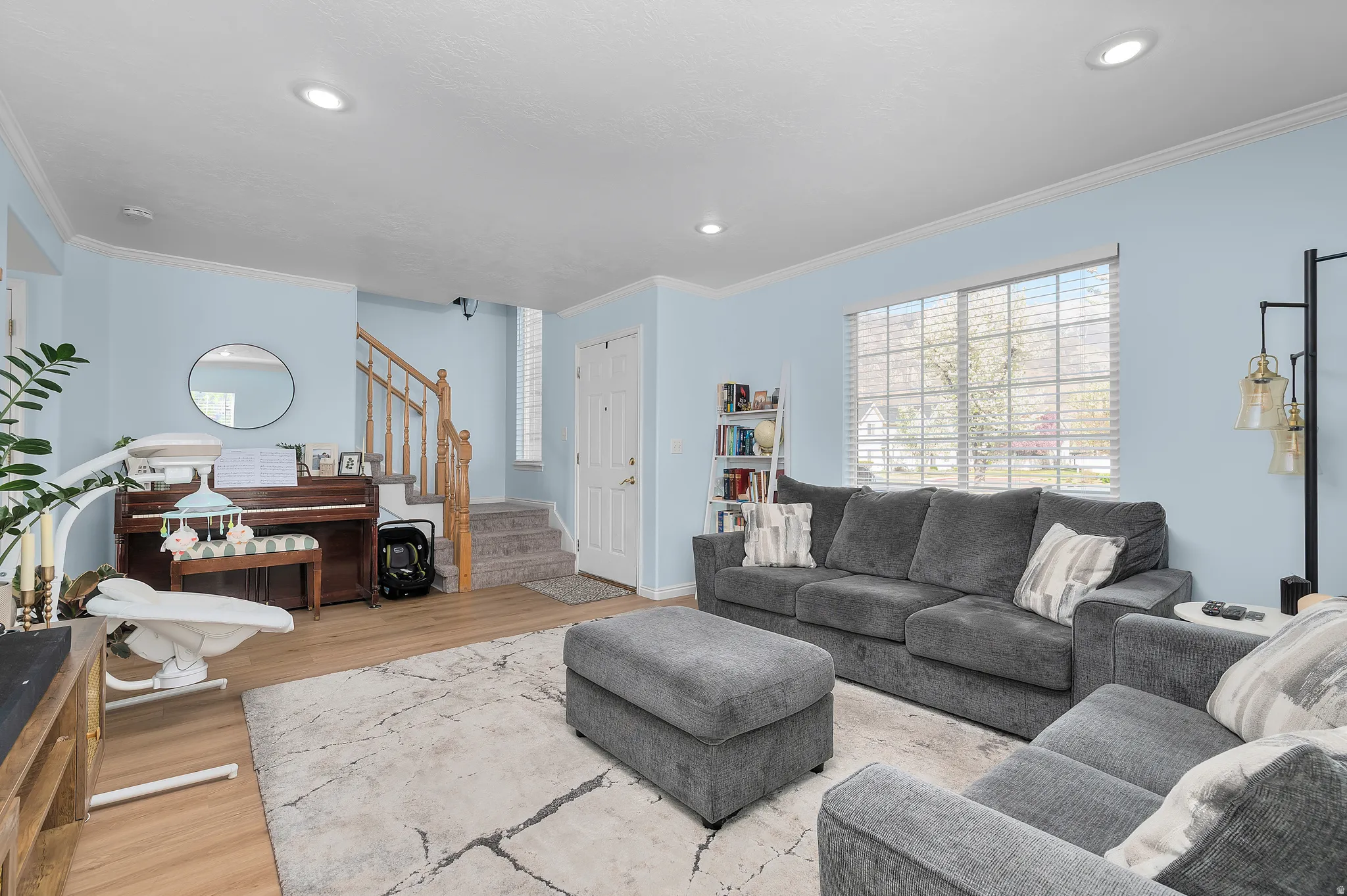 Living area with light wood-style flooring, ornamental molding, and recessed lighting
