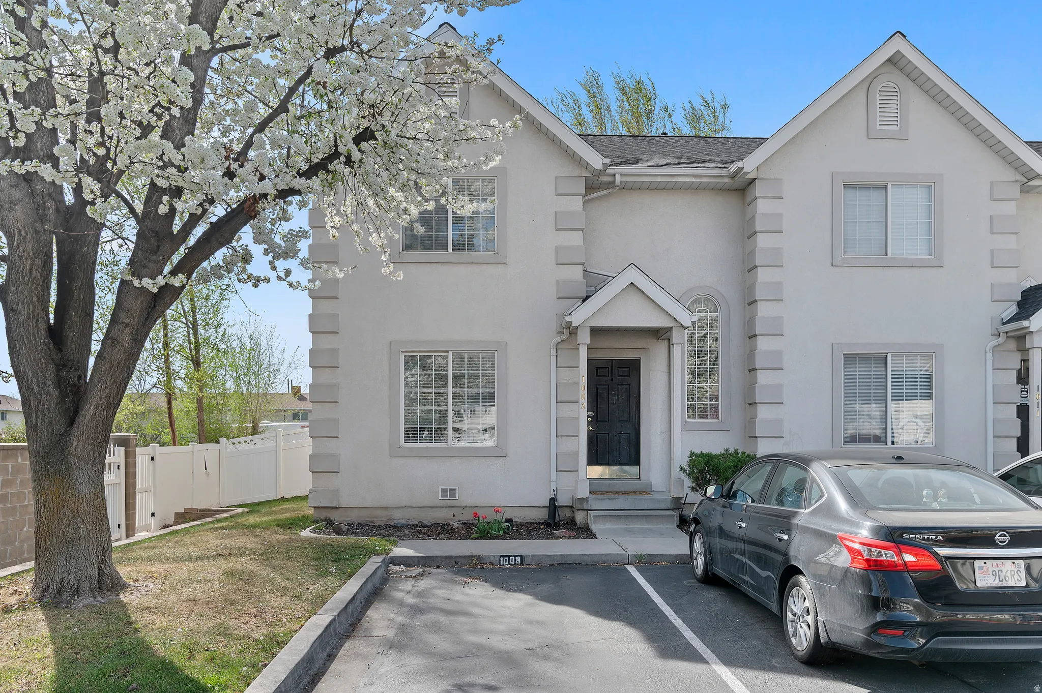 Traditional-style home featuring stucco siding, a gate, a shingled roof, and uncovered parking