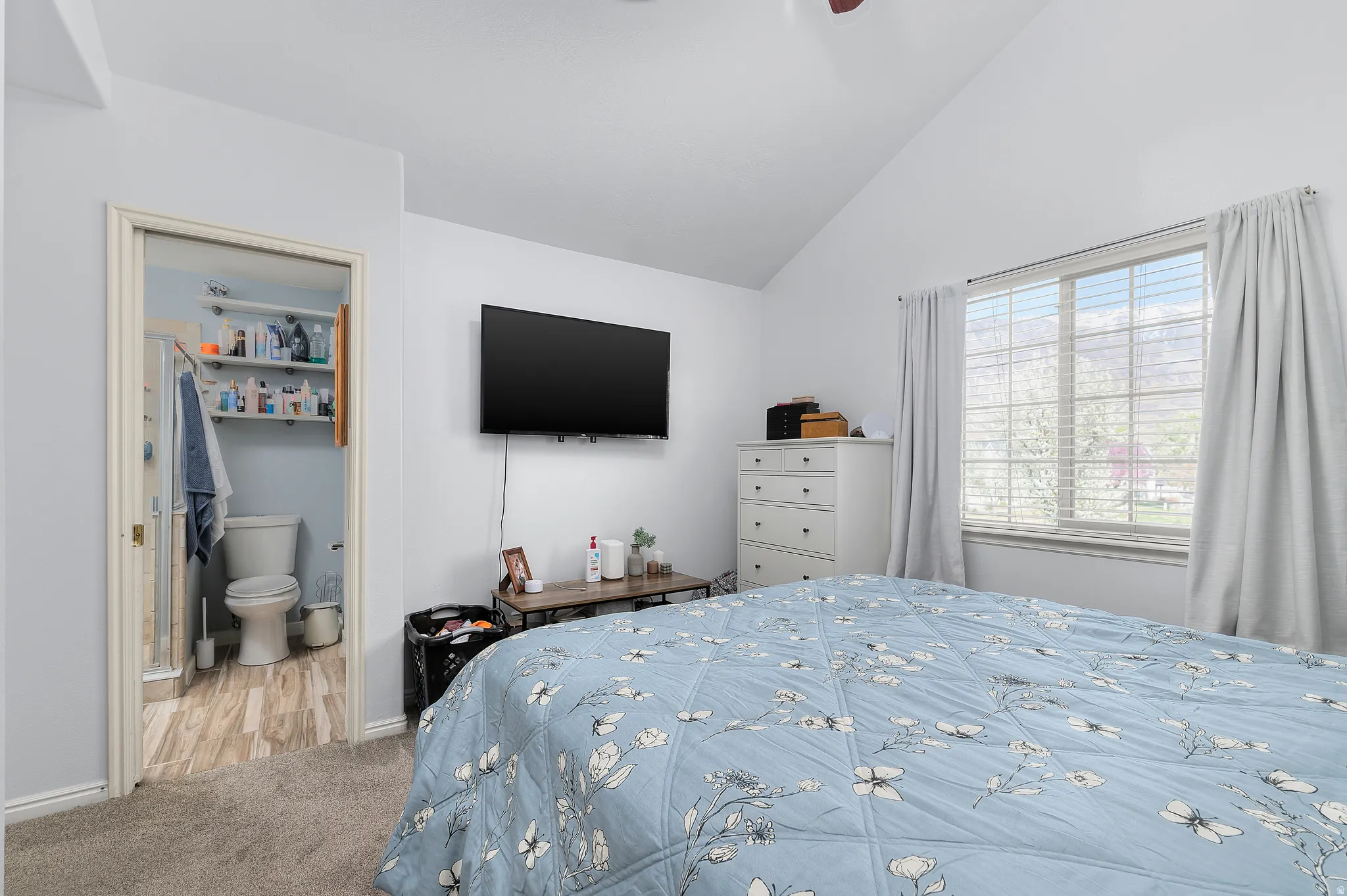 Bedroom with carpet floors, vaulted ceiling, connected bathroom, and a ceiling fan