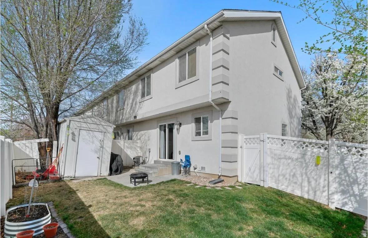 Back of house with a fenced backyard, a gate, a storage shed, a patio area, and stucco siding