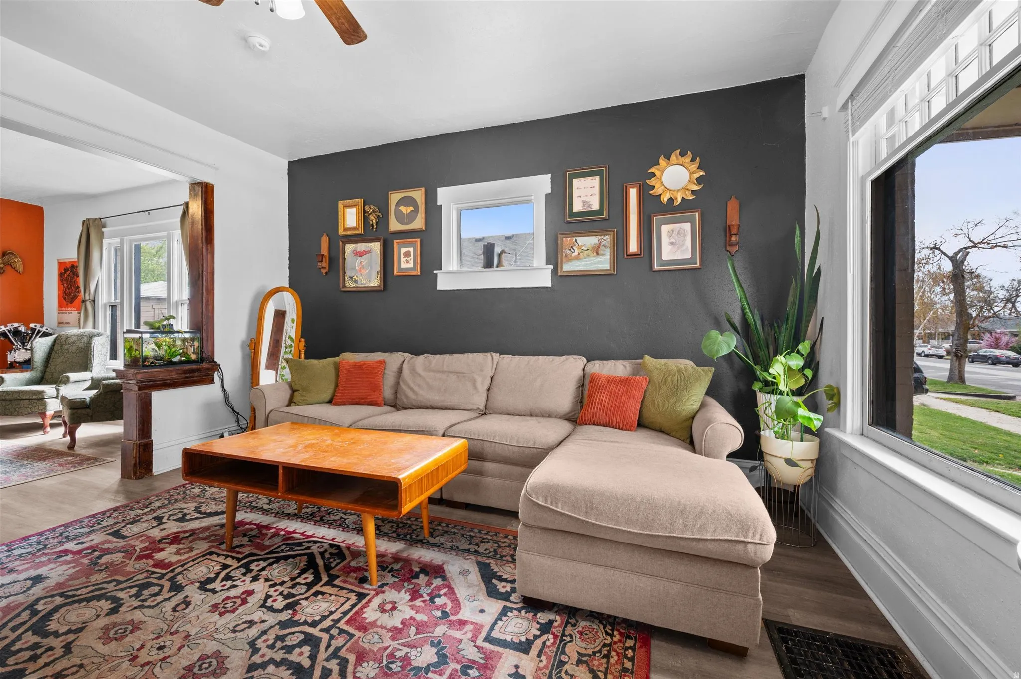 Living area with an accent wall, a ceiling fan, and wood finished floors