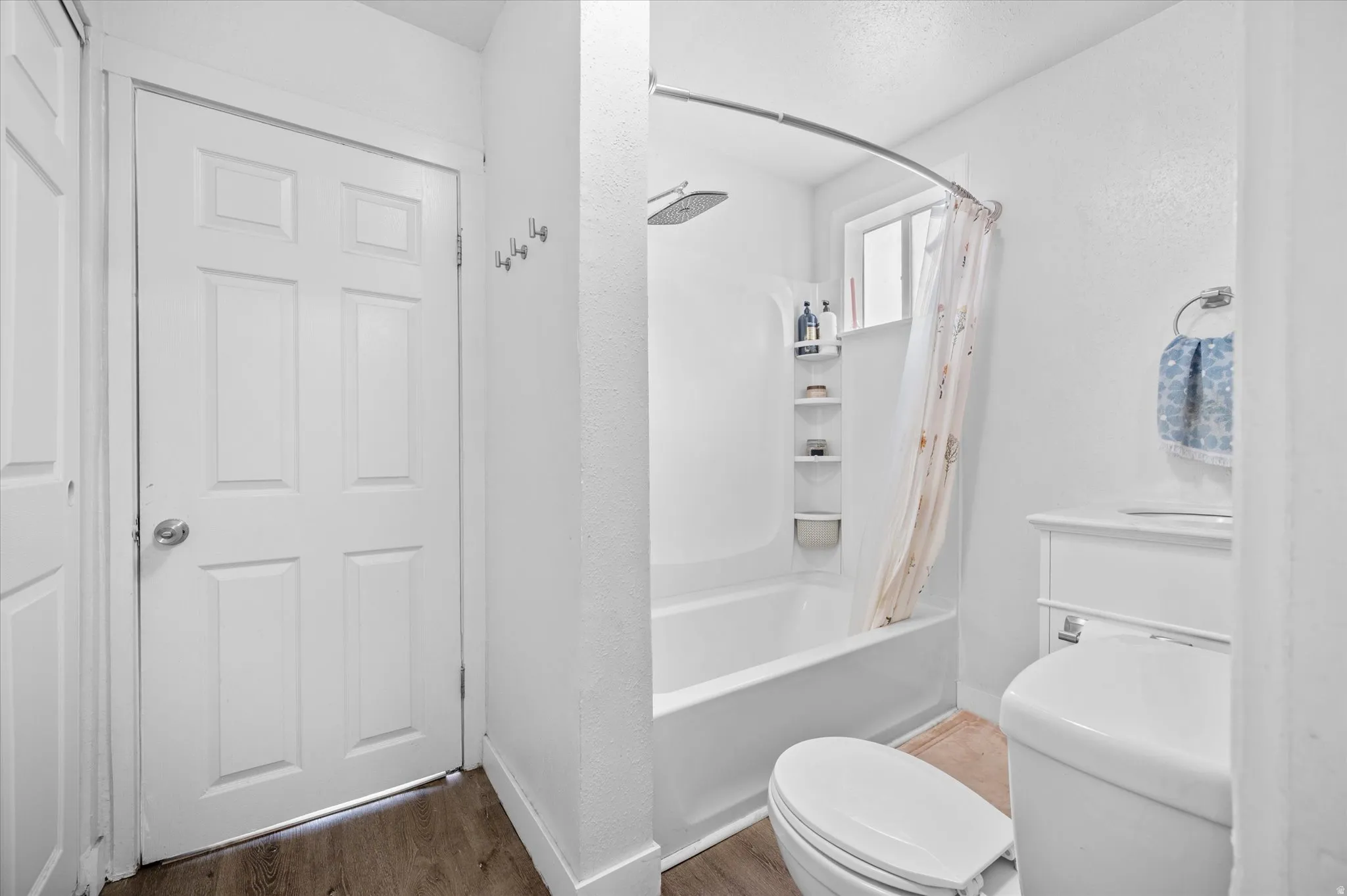 Full bathroom featuring shower / bathtub combination with curtain and light wood-style flooring