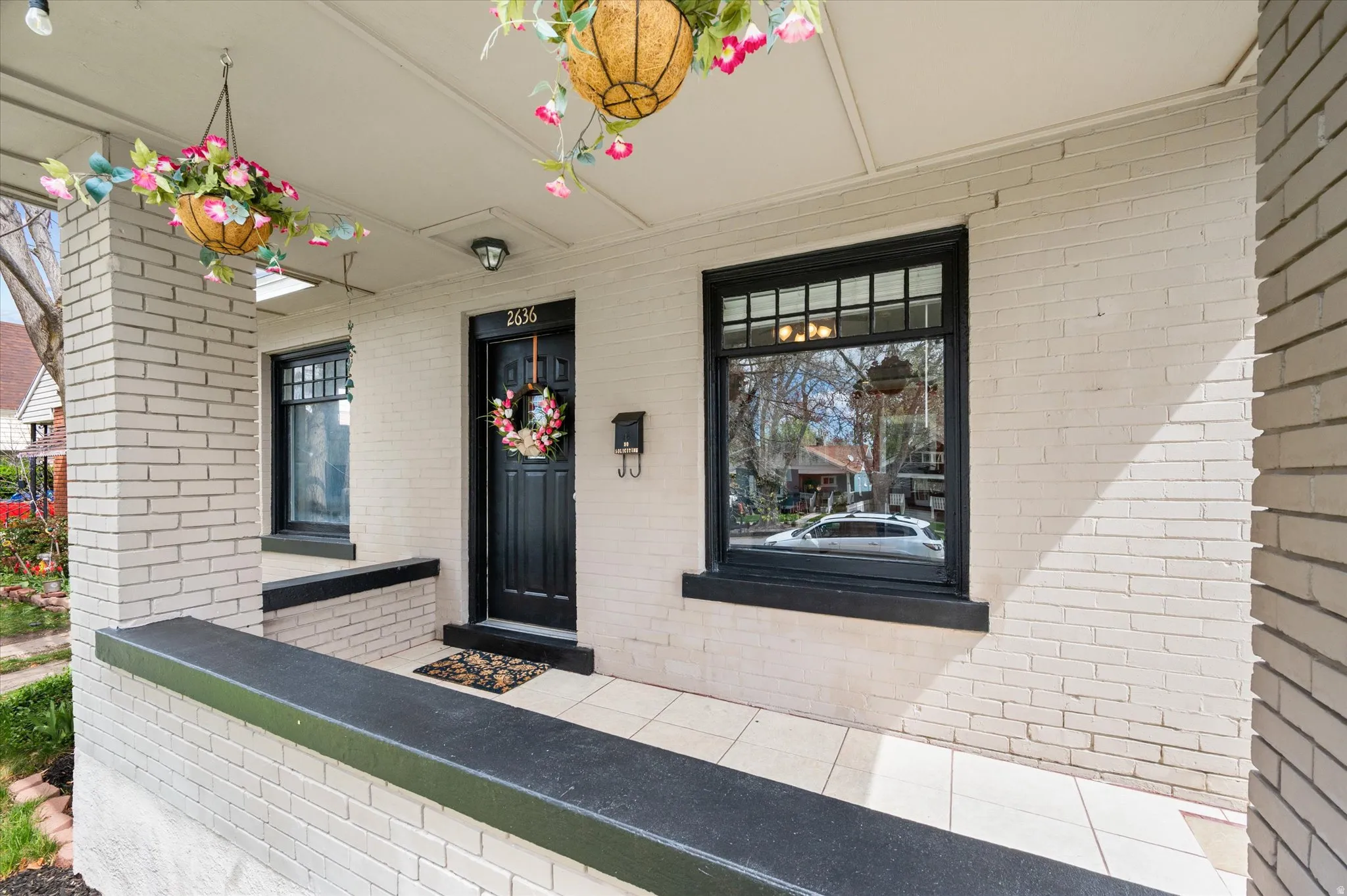 Doorway to property with covered porch and brick siding