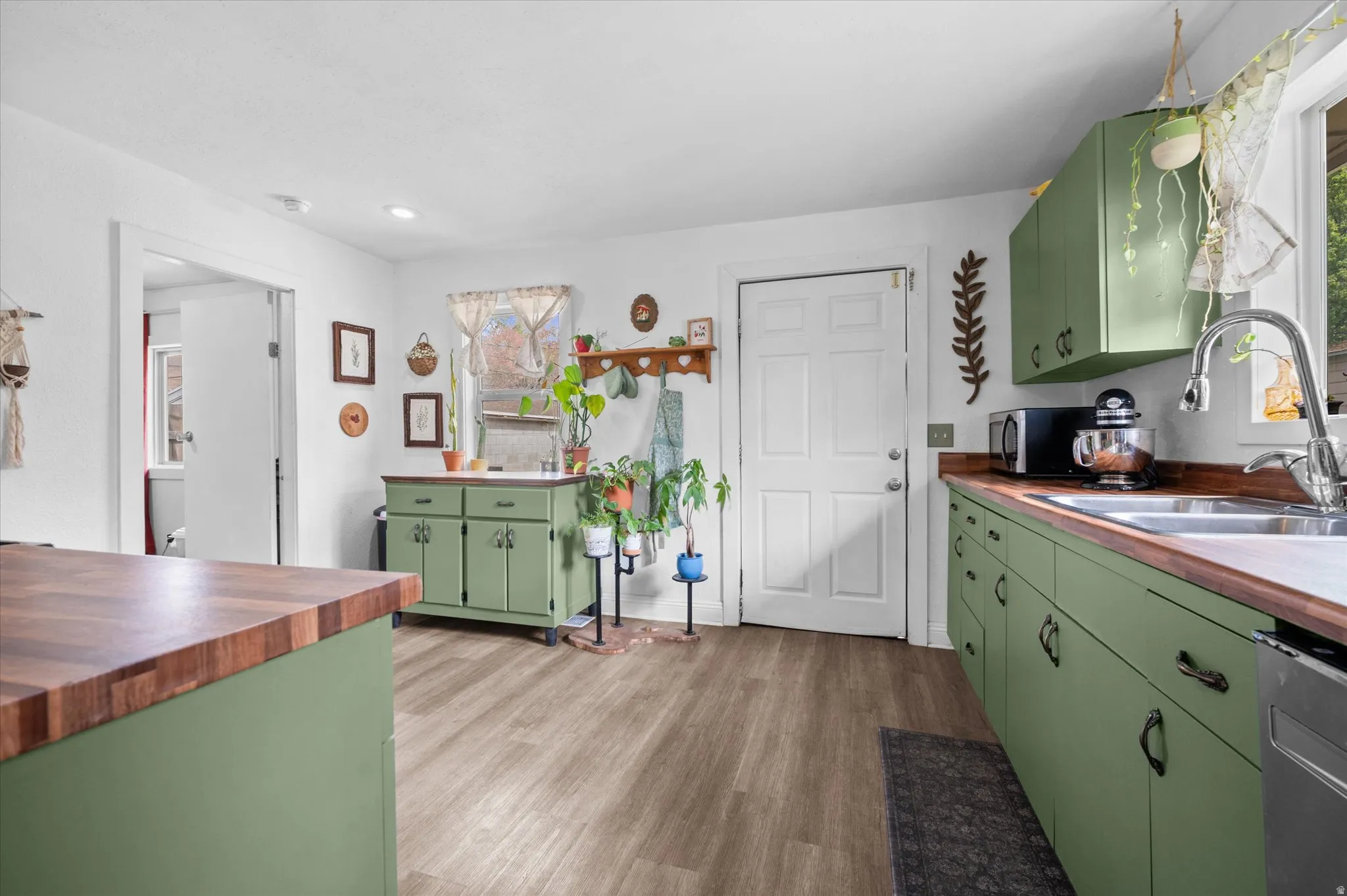 Kitchen featuring green cabinetry, light wood-type flooring, wooden counters, and stainless steel appliances