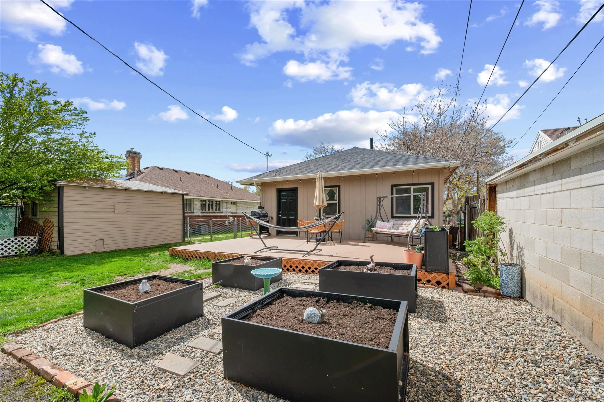 Rear view of house with a patio, a fenced backyard, a garden, a shingled roof, and a shed